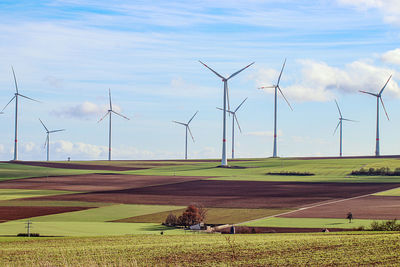 Wind turbines on field against sky