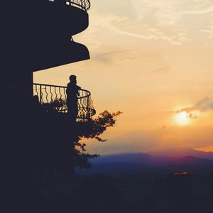 Silhouette man standing by tree against sky during sunset