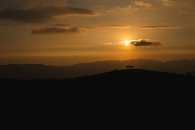 Silhouette landscape against sky during sunset