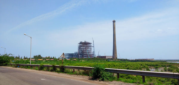 Street by factory against sky