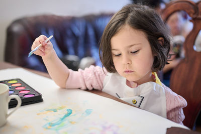 Concentrated girl is painting with watercolors