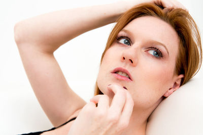 Close-up of thoughtful young woman looking away against white background