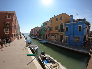 Boats in canal amidst buildings in city against sky