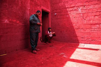 Man crouching while friend standing against wall at home