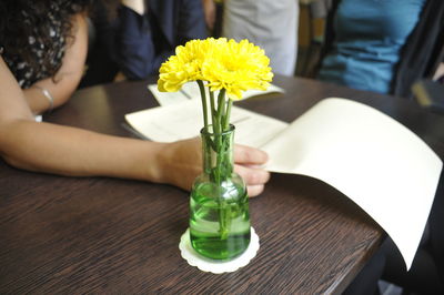 Midsection of business people with document by flower vase on table