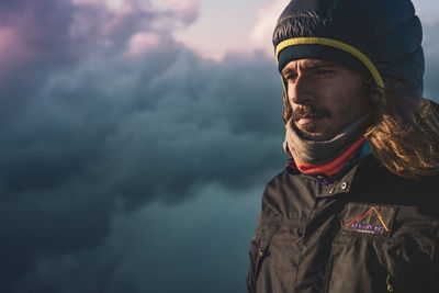 Portrait of young man looking away against sky