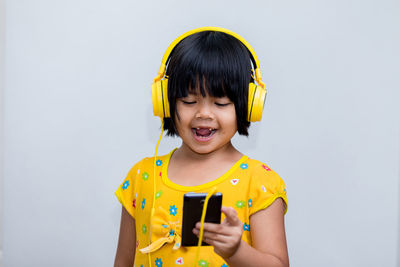 Portrait of boy holding camera while standing against white background