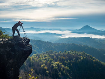 Lone nature photographer traveler take photo of beautiful morning landscape from top of the mountain