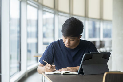 Man looking at camera while sitting on window