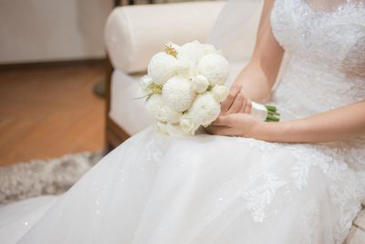 Midsection of white holding bouquet