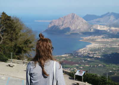 Rear view of woman standing at beach against sky