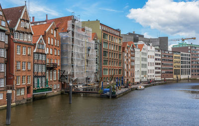 Buildings by canal against sky in city