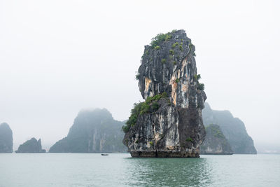 Rock formations in sea against clear sky