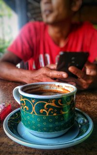 Midsection of woman holding coffee while sitting on table