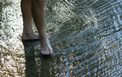 Low section of woman standing in stream