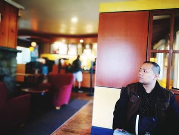 Young man looking away while sitting in restaurant