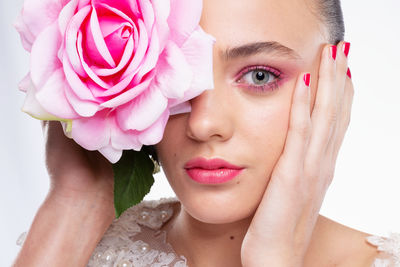 Close-up of young woman with rose against white background