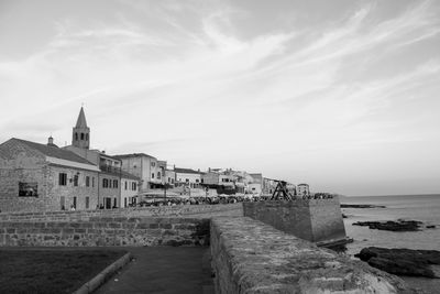 Buildings by sea against sky