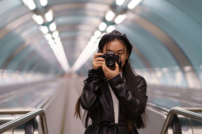 Korean tourist girl make photos travelling. young chinese female hold camera riding on escalator