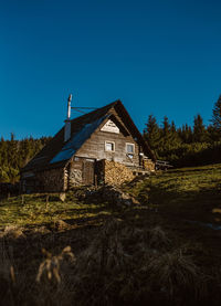 House amidst trees and buildings against clear blue sky