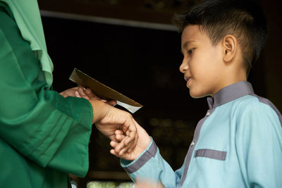 Profile view of malay son greeting and asking forgiveness to mother during ramadan festival 