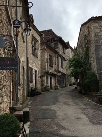 Empty road amidst buildings against sky