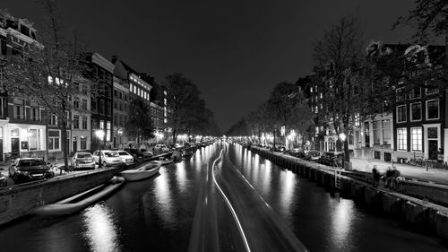 Canal amidst illuminated buildings in city at night