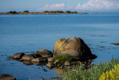 Scenic view of rocks by sea against sky