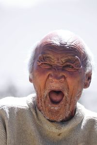 Close-up of old man standing over isolated background bored yawning tired mouth, restless.