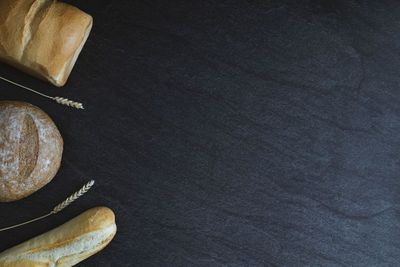 Two breads and one french baguette on a black background.