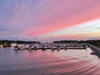 Boats moored at harbor against sky during sunset