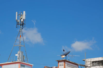 Low angle view of crane by building against blue sky