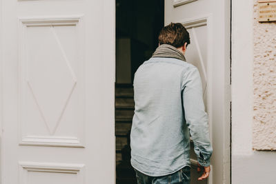 Rear view of young man entering house