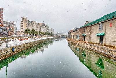 Canal amidst buildings in city during rainy season