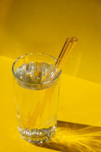 Reusable glass straws in glass with water on yellow background eco-friendly drinking straw set with