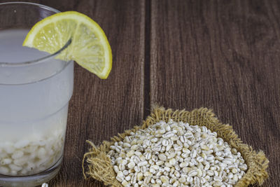 Close up on raw barley wheat placed on brown sack over wooden background