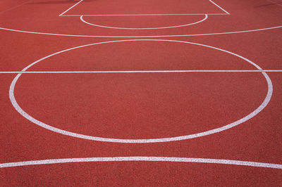 Red plastic covering on the playground, circles and white stripe, basketball court. 