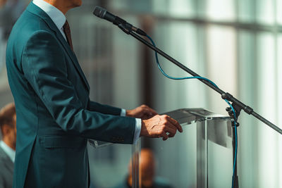 Male speaker wearing suit standing in front of microphones 