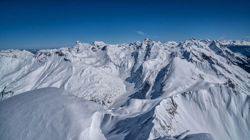 Panoramic view of snowcapped mountains against blue sky