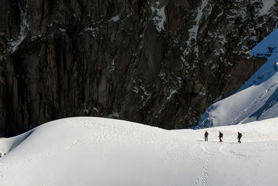 View from aiguille du midi chamonix viewpoint of unrecognizable group of people strolling on snowy slope of mont blanc mountain in nature in winter day