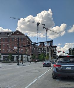 Cars on street by buildings against sky