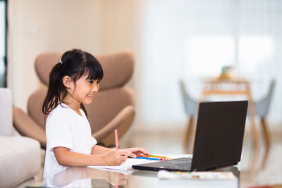 Woman using phone while sitting on table