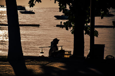 Silhouette people sitting on shore by sea