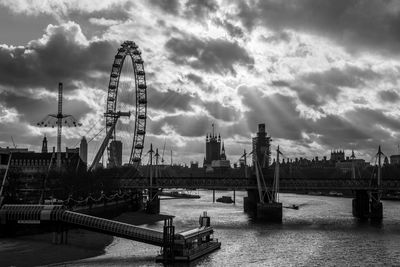 Ferris wheel in city against cloudy sky