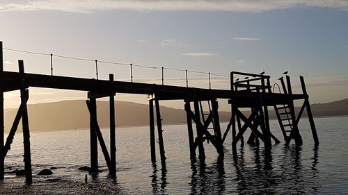 Silhouette pier on sea against sky at sunset