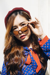 Portrait of young woman wearing sunglasses against wall outdoors