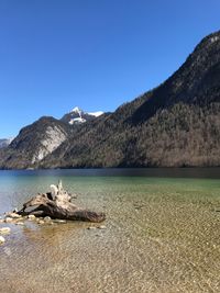 Scenic view of sea and mountains against clear blue sky