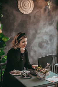 Young woman looking away while sitting on table