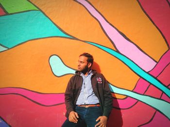 Portrait of young man standing against graffiti