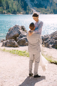 Rear view of couple standing on rock at shore